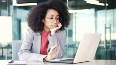 Çok çalışan Afro-Amerikan iş kadını iş yerinde oturmaktan sıkıldı. Uykulu yorgun siyah kadın dizüstü bilgisayarla çalışmaktan yoruldu. Tembel bir işçi oyalanır, dikkati dağılır.