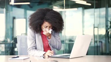 Ofisteki bir iş yerinde dizüstü bilgisayarda çalışan ve mevsimsel alerjisi olan hasta Afro-Amerikalı genç bir iş kadını. Alerjik siyah kadın hapşırır ve burnunu mendille siler.