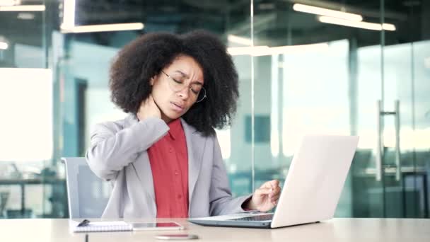 厌倦了的年轻非洲裔美国女商人坐在办公室工作时 在笔记本电脑上工作时脖子感到疼痛 不安的黑人妇女按摩和擦伤肌肉 伸展筋骨 — 图库视频影像