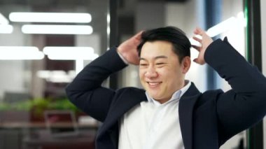 Mutlu Asyalı işadamı iş yerindeki bilgisayarında oturmayı bitirdi. Resmi takım elbiseli tatmin olmuş olgun bir adam ellerini başının arkasına koyup sandalyeye uzanıyor. İş tamamdır. Kapat.