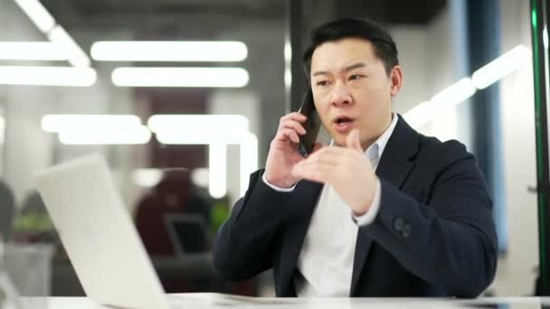 Wściekły Azjatycki Biznesmen Formalnym Garniturze Kłócący Się Telefon Siedząc Biurze — Wideo stockowe