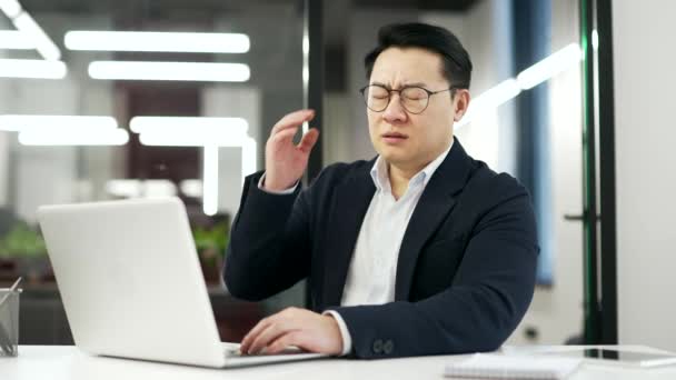 Zmęczony Azjatycki Biznesmen Cierpiący Ból Głowy Podczas Pracy Laptopie Siedząc — Wideo stockowe