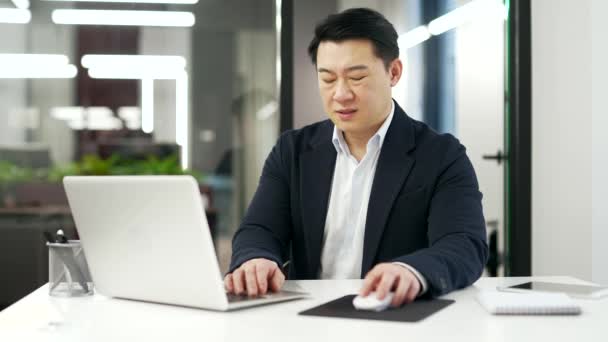 Yerinde Dizüstü Bilgisayarla Çalışırken Bilek Ağrısı Çeken Yorgun Asyalı Adamı — Stok video