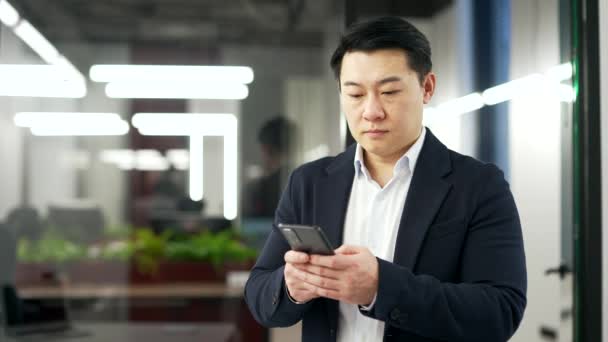 Komoly Ázsiai Üzletember Használja Telefont Miközben Üzleti Irodában Áll Koncentrált — Stock videók