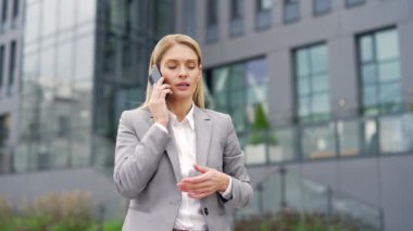 İş kadını bir ofis binasının yanında caddede dikilirken telefonda konuşuyor. Resmi takım elbiseli bir kadın müşteriyle ya da arkadaşıyla konuşuyor, iş ortağıyla sohbet ediyor.
