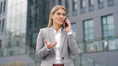 Öfkeli iş kadını, bir ofis binasının yakınındaki caddede akıllı telefondan konuşurken tartışıyor. Resmi takım elbiseli heyecanlı bir kadın telefona bağırıyor, tartışıyor ve bir sorun olduğunu söylüyor.