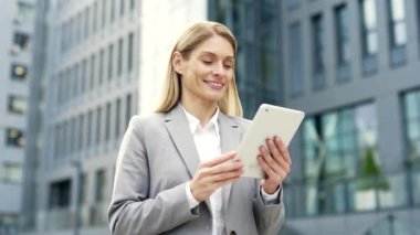 Resmi takım elbiseli mutlu işadamı bir ofis binasının yanındaki sokakta duran dijital tableti kullanıyor. Kadın okuma, istemciyle sohbet eden, mesajlaşan ya da internette gezinen bir mesaj yazar. Kapat.