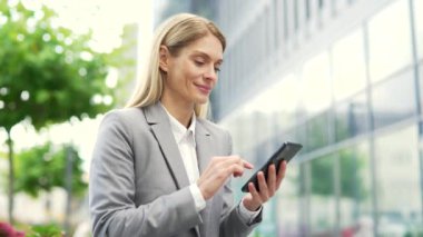 Mutlu iş adamı bir ofis binasının yanındaki caddede duran telefonu kullanıyor. Resmi takım elbiseli kadın yönetici mesajlar yazar, mesajlaşır, mesajlaşır, mesajlaşır, e-postaları kontrol eder ya da internette gezinir. Kapat.