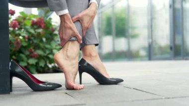 Kapatın. Kadın eli, bacak kaslarına masaj yapıyor. İş kadını bacak ağrısı çekiyor, baldır kası spazmı sokakta bir bankta çıplak ayakla oturuyor. Baldırlardaki tendonların iltihaplanması sonucu travma.