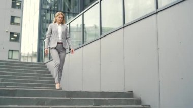 Resmi takım elbiseli kendine güvenen bir iş kadını ofis binasının önündeki merdivenlerden aşağı iniyor. Ciddi bir bayan girişimci toplantıdan dönüyor. Kadın müdür öğle yemeğine gidiyor.