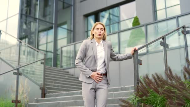 オフィスビルの階段の外を歩いている間 胃の痛みに苦しんでいる病気のビジネスマン 女性は胃炎 消化器系の問題 関節炎または月経を持っています — ストック動画