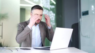 Hüsrana uğramış işadamı iş yerinde otururken dizüstü bilgisayarından kötü haberler okuyor. Takım elbiseli hayal kırıklığına uğramış bir adam bilgisayardaki olumsuz bilgiyi incelediği için üzgün.