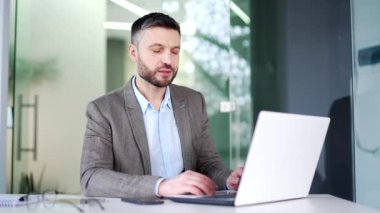 Ofisteki bir iş yerinde dizüstü bilgisayarla konuşan kendine güvenen bir iş adamı. İşçi bir adamın iş görüşmesi var, uzaktan konuşuyor, online bir konferansta iletişim kuruyor.