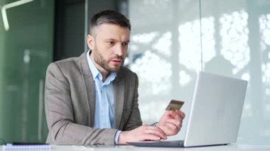 Şok olmuş işadamı iş yerindeki bilgisayarından kredi kartını kontrol ediyor. Hüsrana uğramış işçi dolandırıcılıkla yüzleşti, hesabından para çalındı. Aldatılmaya kurban gitti.