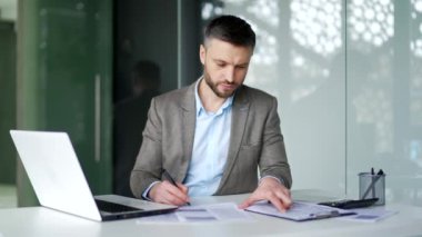 İş yerindeki bir masada otururken ceketli bir işadamı evrak işleriyle uğraşıyor. Güvenilir yatırımcı ya da muhasebeci evrakları doldurur, yazar, vergi beyannamesi yapar.