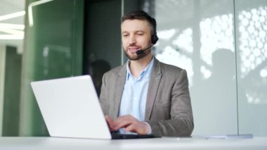 Müşteri hizmetlerinde çalışan bir şirket operatörü bilgisayar kullanarak bir video görüşmesinde konuşuyor. Kablosuz kulaklık takmış bir merkez ajanı ofisteki müşterilere şikayette yardımcı oluyor. Çevrimiçi danışma
