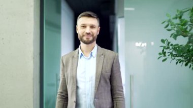 İş yerinde kollarını kavuşturup duran mutlu iş adamının portresi. Kameraya bakarak gülümseyen başarılı bir çalışan. Yakışıklı sakallı menajerin resmi.
