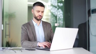 Ciddi düşünceli bir iş adamı bir iş yerindeki bir laptopta çalışıyor. Resmi takım elbiseli müdür bir sorunu çözmeyi düşünüyor. Bilgisayardaki başlangıç projesiyle meşgul.