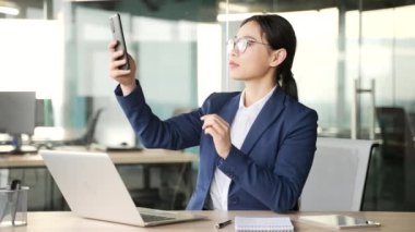 Asyalı işkadını iş yerindeki cep telefonunu kullanarak Wi-Fi sinyali alamamaktan şikayetçi. Şaşkın kadın işçi akıllı telefonun çalışmasından memnun değil.