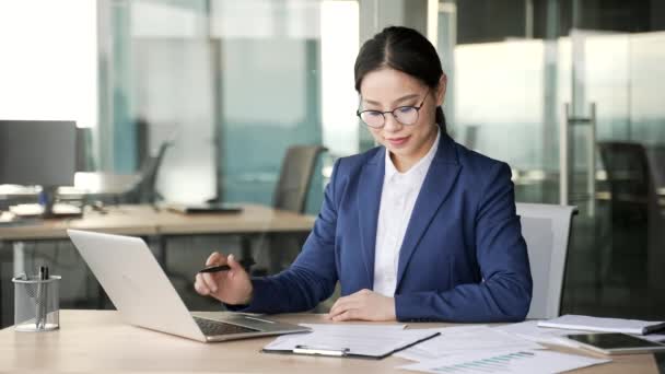 忙碌的亚洲女商人坐在办公室工作时 用笔记本电脑填写文档 戴眼镜 做文书工作 填写财务报告或填写税单的女金融家 — 图库视频影像