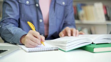 Kapatın. Üniversite kütüphanesindeki bir not defterine kalemle yazan bir kadın. Öğrenci ders kitabı okuyor, not alıyor, sınav dönemini öğreniyor. Başvuru sahibi giriş sınavları için hazırlanır