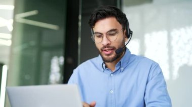 Müşteri hizmetlerinde çalışan bir şirket operatörü bilgisayar kullanarak görüntülü konuşma yapıyor. Kablosuz kulaklıklı merkez ajanını ara, ofisteki şikayetlere yardım et. Online danışmanlık. Kapat.