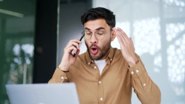 İş yerinde otururken cep telefonuyla konuşan kızgın iş adamı. Tatminsiz patron, çözülmesi gereken sorunlar hakkında astlarıyla duygusal olarak konuşur.