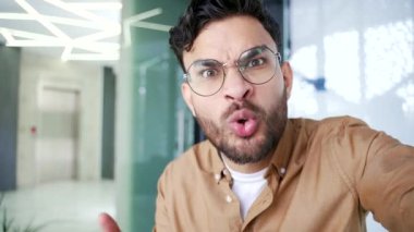 Bakış açısı. Sinirli iş adamı iş yerinde cep telefonuyla görüntülü konuşma konusunda tartışıyor. Tatminsiz patron, alt tabakadan biriyle kameraya bakan problemler hakkında konuşuyor.