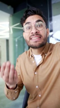 POV dikey video. Sinirli iş adamı iş yerindeki telefonla telefonda konuşurken tartışıyor. Tatminsiz patron, bir astıyla kameraya bakma sorunları hakkında duygusal olarak konuşur.