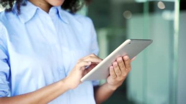 İş yerinde dijital tablet kullanarak kadınların ellerini tutun. Afrikalı Amerikalı kadın çalışan bilgisayar uygulaması üzerinde çalışıyor, mesaj yazıyor, internette sohbet ediyor, geziniyor, e-postaları kontrol ediyor.