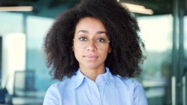 Kendine güveni tam genç bir Afro-Amerikan çalışanının portresi iş ofisinde duruyor. Gözlüklü ciddi bir zenci kadın kameraya bakıyor. Başarılı bir öğretmenin vesikalığı. Kapat.