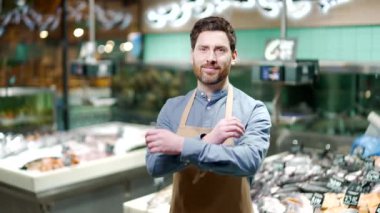 Deniz ürünleri pazarında çalışan yakışıklı bir adam portresi ya da süpermarket balıkçısı. Küçük işletme sahibi, gülümseyen ve kameraya bakan bir adam.