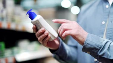 Yakından bakan adam kompozisyon ürünü şampuanını inceliyor Erkek Müşteri Markette Kozmetik Şişesi Etiketini okuyor Süpermarket Çalışmaları 'nda bilgiler okunuyor.