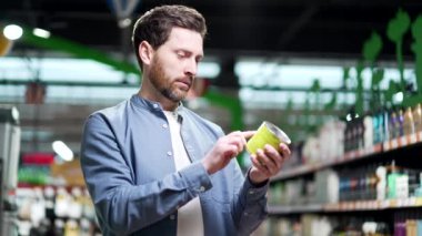 Adam ürün ürünlerinin bileşimini inceliyor. Market araştırmalarında konserve konservelerin üzerinde 