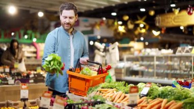 Müşteri alıcısı markette, markette ya da süpermarkette taze sebze seçer. Bir erkek, elinde bir sepetle bir perakende mağazasından günlük alışverişler yapar ve seçtiği ürünü seçer. 