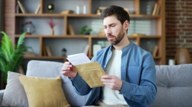 Evdeki kanepede oturmuş, kötü haberlerle mektup okuyan yakışıklı adam hayal kırıklığına uğradı. Üzgün sakallı bir erkek, kötü bir haber yüzünden depresyona girer. Belgelerdeki bilgilere göre kameraya bakarken şok olur.