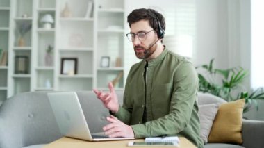 Kablosuz kulaklık takan kendine güvenen iş adamı bilgisayarla ev ofisini arıyor. Girişimcinin ortağıyla online iş görüşmesi var. Satıcı müşteriyle uzaktan konuşuyor.