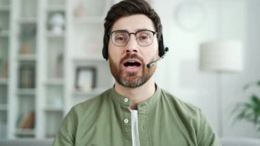 Webcam görüntüsü. Kablosuz kulaklık takmış kendine güvenen iş adamı merkez ofisteki kameraya bakarak bir video görüşmesi yapıyor. Girişimcinin iş toplantısı var. Öğretmen çevrimiçi bir kursta uzaktan konuşuyor. Kapat.