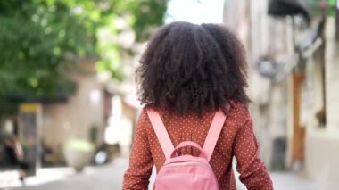Çekici genç Afrikalı Amerikalı kadın şehir caddesinde yürüyor, kameraya dönüp gülümsüyor ve dışarıda mutlu bir bayan turist portresi çiziyor. Şehirde iyi vakit geçiriyor. Buraya gel, beni takip et.