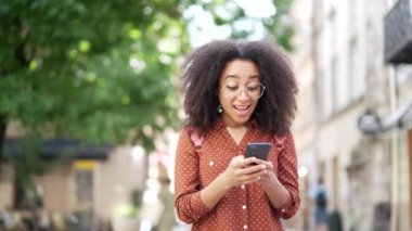 Zaferi kutlayan neşeli genç kadın telefonda harika haberler okuyor. Tatmin olmuş kız öğrenci, dışarıdaki bir caddede duran akıllı telefona bakarak olumlu bir mesaj alıyor.