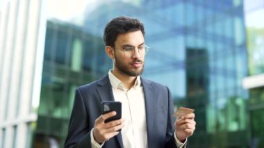 Takım elbiseli bir işadamı, bir iş yeri binasının yakınındaki bir sokakta dururken kredi kartı numarasına giriyor. Yakışıklı sakallı adam internetten alışveriş yapıyor. İyi fiyat ve terfilerden memnun.