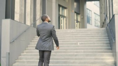 Açık şehir ortamında merdivenlerden yukarı çıkan Afro-Amerikalı işadamı, telefon konuşmalarıyla meşgul. Profesyonel davranışları, kasıtlı hareketleri ve modern yaşam tarzını yakalıyor. Arka plan görünümü