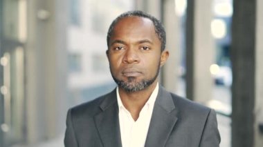 Dışarıda iş kıyafetleri içinde dururken gülümseyen kendine güvenen Afro-Amerikan portresi. Profesyonel görünüş başarıyı ve ulaşılabilirliği temsil eder. Ofise yakın başarılı bir kariyer.