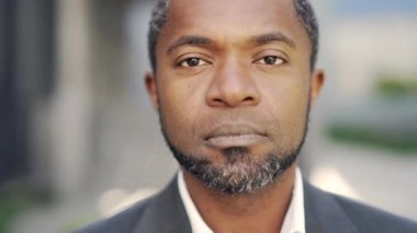 Açık havada iş kıyafetleri içinde gülümseyen olgun Afro-Amerikan bir adam. Şehir ortamında güven ve pozitifliği yakalar. İş, başarı ve pozitiflikle ilgili konular için ideal
