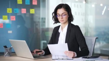 Profesyonel kadın muhasebeci ofis ortamındaki mali belgeleri analiz eder. Kadınlar dizüstü bilgisayar kullanarak modern iş ortamını sergiliyorlar. İşine odaklanmış yetenekli muhasebe uzmanı..