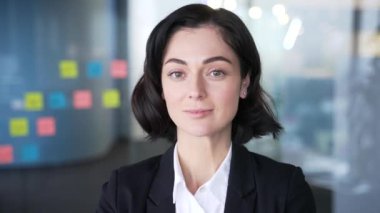 Modern ofis ortamında kendine güvenen bir iş kadını portresi. Profesyonel kadın resmi giyinmiş, özgüven ve kararlılık saçıyor. İş, iş ve kurumsal temalar için mükemmel.