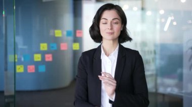 Modern ofiste kollarını kavuşturmuş kendine güvenen bir iş kadınının portresi. Ciddi genç bayan müdürün vesikalığı. İş kıyafeti giymiş profesyonel bir kadın, liderlik ve başarıyı temsil ediyor.