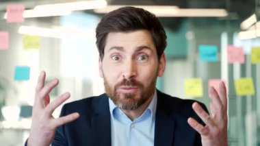 Webcam görüntüsü. Resmi takım elbiseli kızgın işadamı iş yerindeki iş yerinde kameraya bakarak tartışıyor. Heyecanlı patron, astlarıyla sorunlar hakkında konuşuyor.