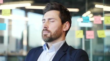 Resmi takım elbiseli bir işadamının ofiste gözleri kapalı otururken rahatlaması. Sakin, mutlu işçi dinleniyor. Derin nefes alıyor. Klimanın serin havasının tadını çıkarıyor.