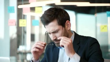 İş yerinde çalışırken baş ağrısı çeken bir iş adamı. Yorgun işçi gözlüğünü çıkarıp, şakaklarına elleriyle masaj yapıyor. Çok yoruldu. Yüksek tansiyon. Kapat.